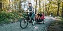 A person riding a bike with a child carriage on the back at Wyre Forest  (credit - Forestry England)