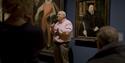 A man doing BSL to a group of people inside the National Portrait Gallery