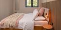 Double bed with pink blanket and cushions
