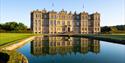 Longleat House in front of a lake with the house reflected in the water at Longleat