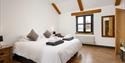 Coach House Cornwall Double Bedroom with a white bed and some grey towels folded on top