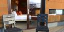Chairs on the decking outside HEX Hotel at Yorkshire Wildlife Park with the patio doors open and leading into the double bedroom