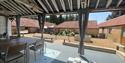 Undercover decking area showing a table and chairs Sparham Hall Farm Holidays