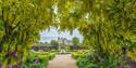 A canopy of trees framing the house and fountains at Helmsley Walled Gardens