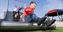 Two children playing on a slide at a playground with clear skies.