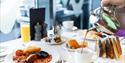 Table set for breakfast at The Royal Yacht Hotel with a full english, toast and someone pouring a cup of tea