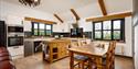 Coach House Cornwall Kitchen shows a wooden table and island in the kitchen with some exposed beams.