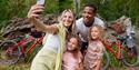 A family taking a selfie Cardinham Woods with their bikes in the background
