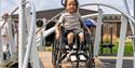Child in a wheelchair on an accessible playground ramp.