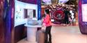 
a girl in a pink top is playing with an interactive display alone.
