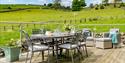 A 6 set table on the decking overlooking fields and blue skies at Hoe Grange Holidays