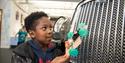 A child with a toy car looking at the exhibits at Coventry Transport Museum