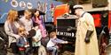 A child in a wheelchair has a go at moving the starting lever on a vintage car at British Motor Museum