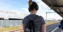 Person stood on train platform with a GWR sensory bag and a pair of headphones