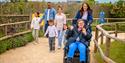 A group of people following the path at Fairytale Farm, with one girl in a wheelchair in front