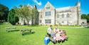 Family enjoying a picnic outside a heritage building at John Fowler Holiday Parks