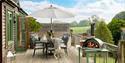 Decking at Hoe Grange Holidays showing a table with a parasol providing shade and a pizza oven
