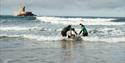 A disabled person playing in the ocean with instructors at Jersey