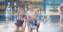 Image of a young girl and boy in a splash zone at a theme park