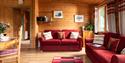 The living room at Hoe Grange Holidays with red sofas and a red rug in the centre of the room