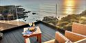 Decking at Watersmeet Hotel with drinks and food on the table as the sunsets over the bay