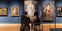 Two people in wheelchairs admiring a portrait of Elizabeth I at the National Portrait Gallery