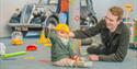 A small child playing with a hard hat and other toys with their parent at Coventry Transport Museum