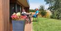 couple on decking outside The Granary, Larkbeare Grange in the sunshine