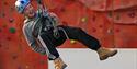 Person posing in ropes near rock climbing wall at Calvert Exmoor