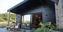 Front view of Oak Tree Cabin, with two chairs on the decking. The entrance to the cabin is flat.