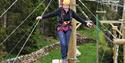Person balancing on a wooden plank with wires around them at Calvert Kielder