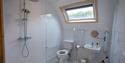 Bright accessible bathroom with walk-in shower, grab rails, toilet, sink, skylight, and toiletries; clean, practical, welcoming space.
