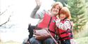 A woman in a wheelchair wearing a life jacket hugs a small child, also in a life jacket at Calvert Kielder