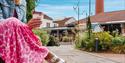 A lady in a pink skirt holding a take away coffee at Clarks Village