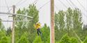 A person wearing a yellow coat using the zip wire at Calvert Kielder