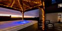 Hot tub at Elderburn Lodges under a cover which has golden fairy lights on.