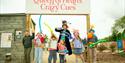Six children with balloon swords stand in front of a sign reading 'Queen of Hearts Crazy Cues' with the Mad Hatter