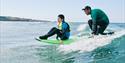 a disabled child surfing with an instructor in the ocean with Healing Waves