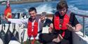 two people wearing life jackets in the back of a boat with Wetwheels Jersey