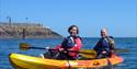 a couple passing the jetty in a kayak with Jersey Kayak Adventures Ltd