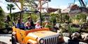 a family driving a car through a dinosaur themed section of Paultons Park