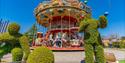 A merry go round next to topiary depicting people working out at Paultons Park