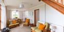 Hall Farm Cottage Living Room with two sofas and a chair. The sofas are light green with orange cushions