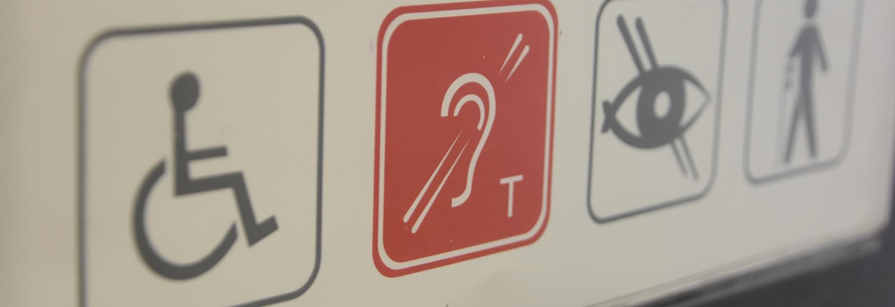 Accessibility sign showing wheelchair, hearing loop and braille