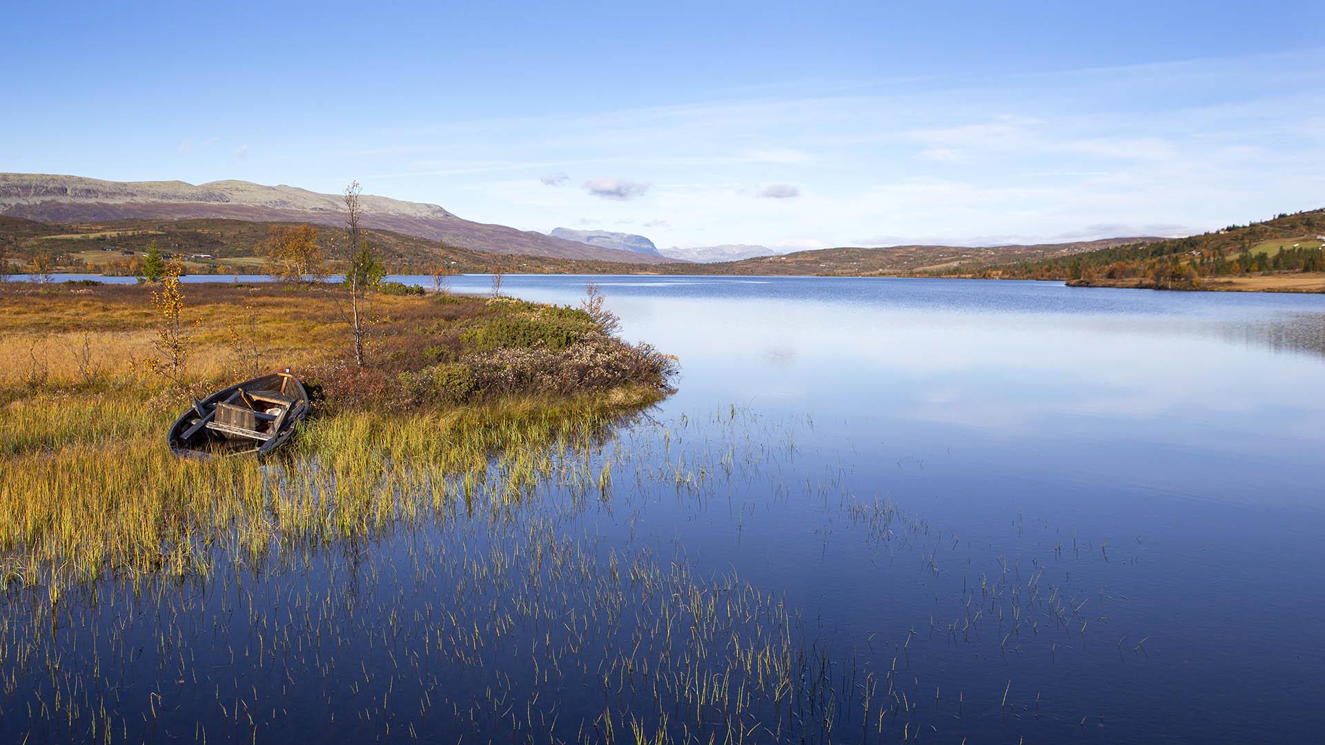 Fjellvann om høsten med en gammel trebåt