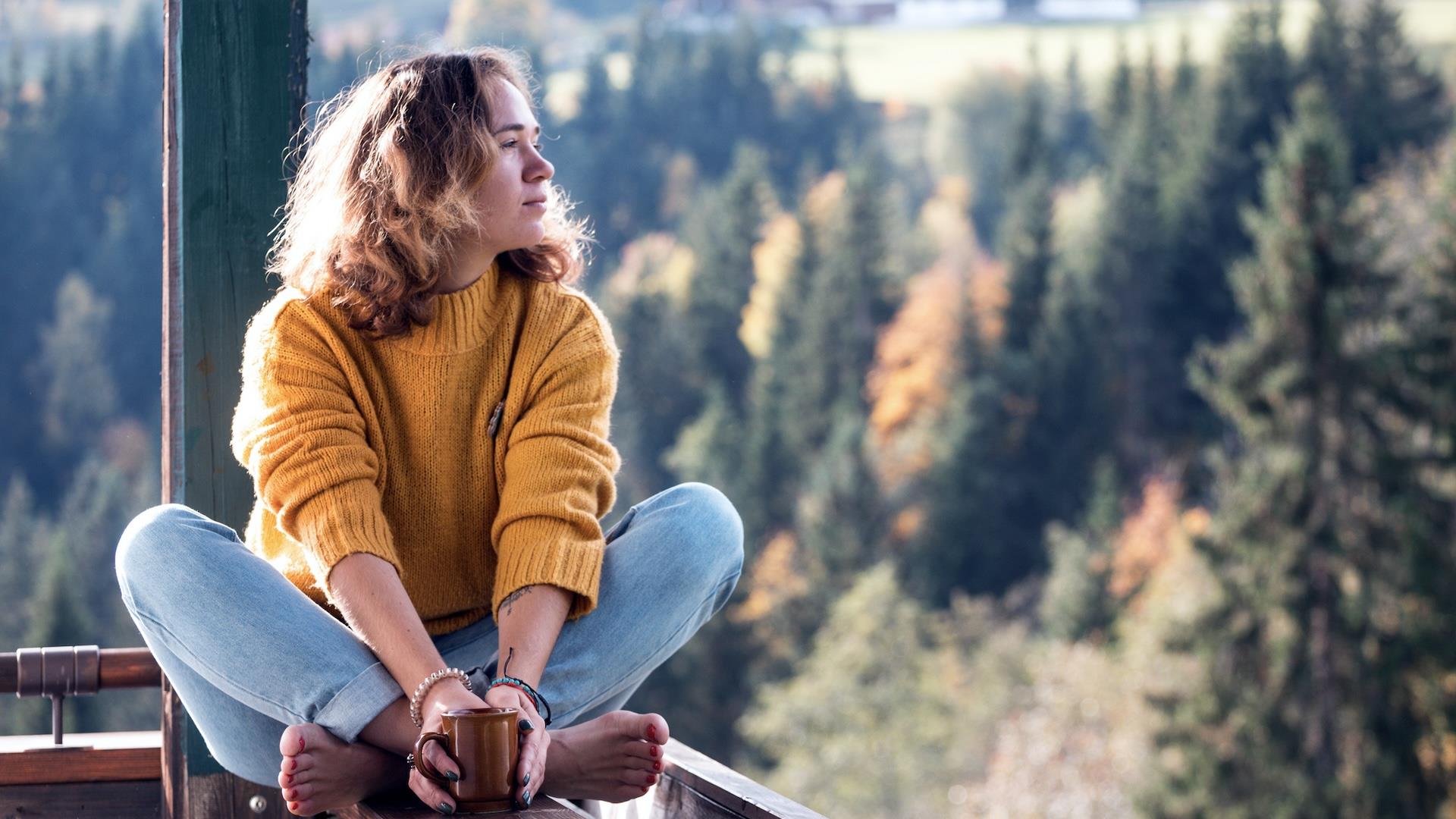 Person sitter på verandaen sin og ser utover landskapet