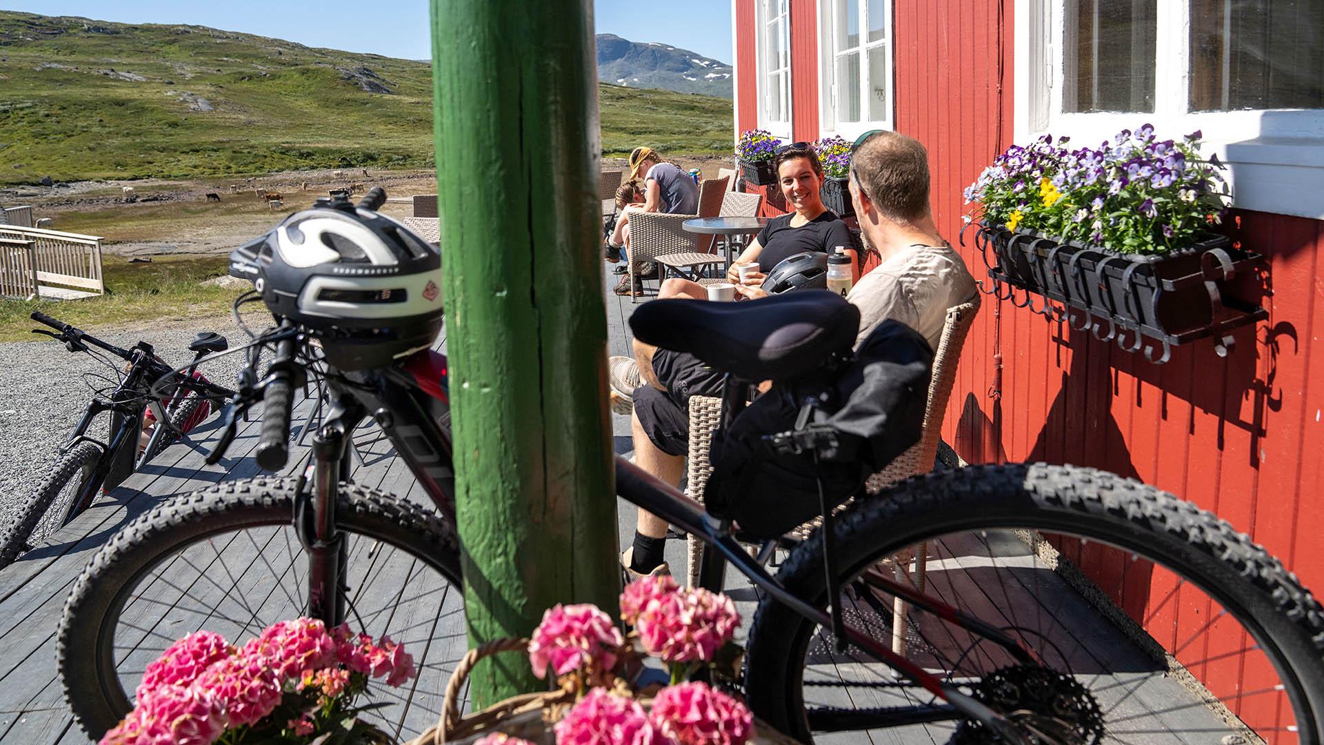 Cyclists on a lunch break on the sunny deck of a mountain lodge