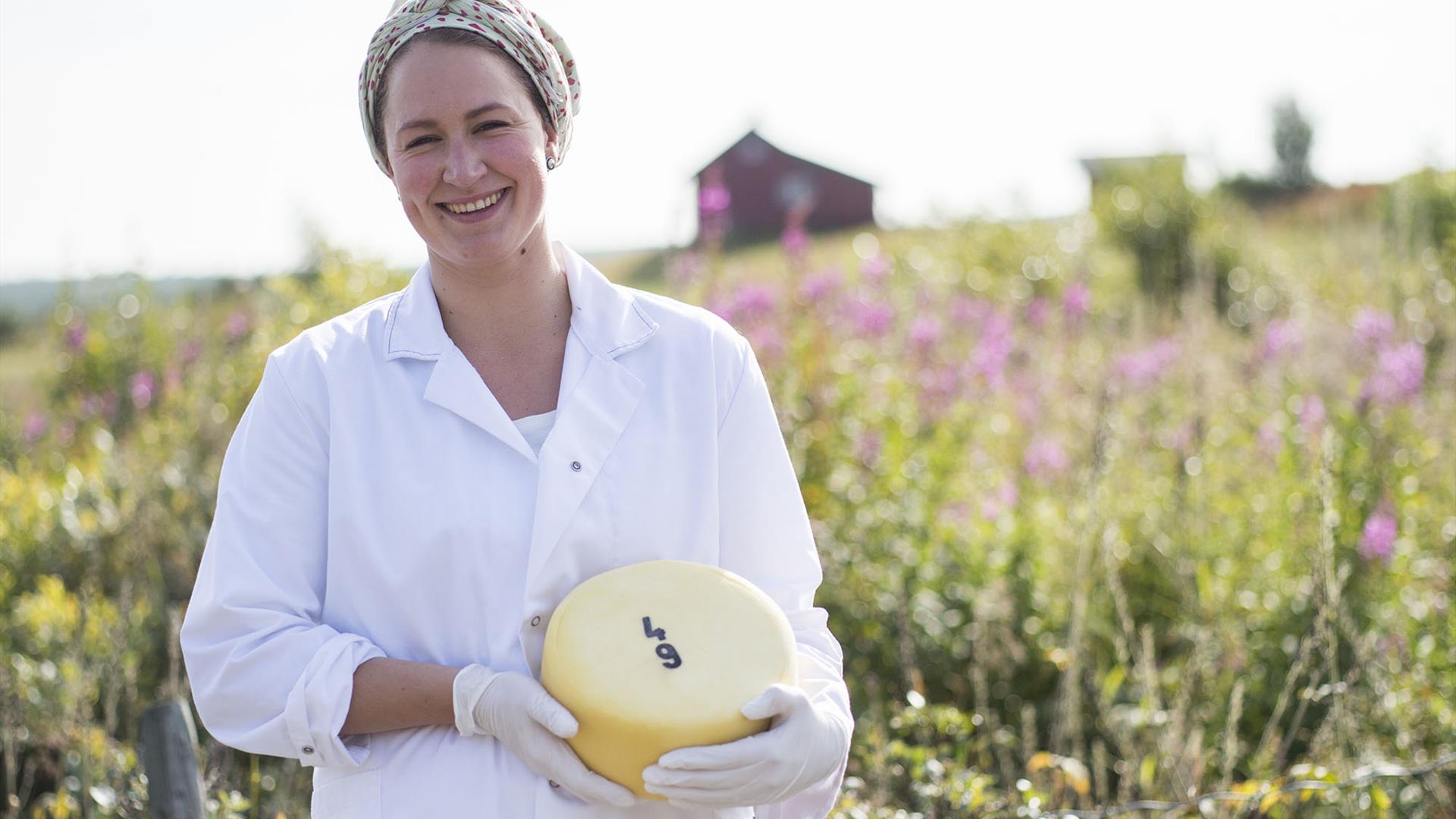 En kvinne i en blomstereng med et ostehjul i hånda