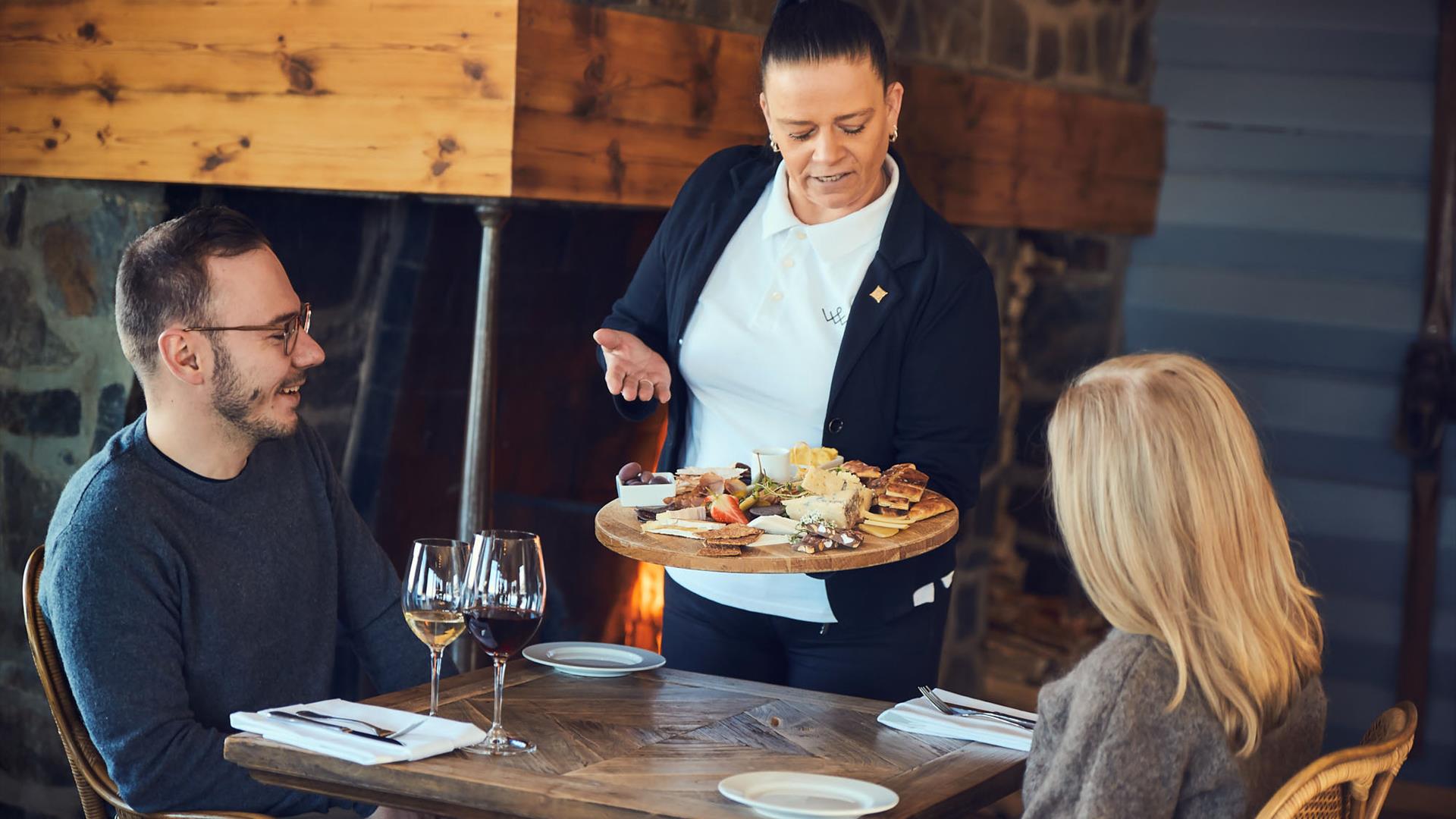 Et par ved bordet i et hotellrestaurant blir servert en tapastallerken av lokal spekemat og oster