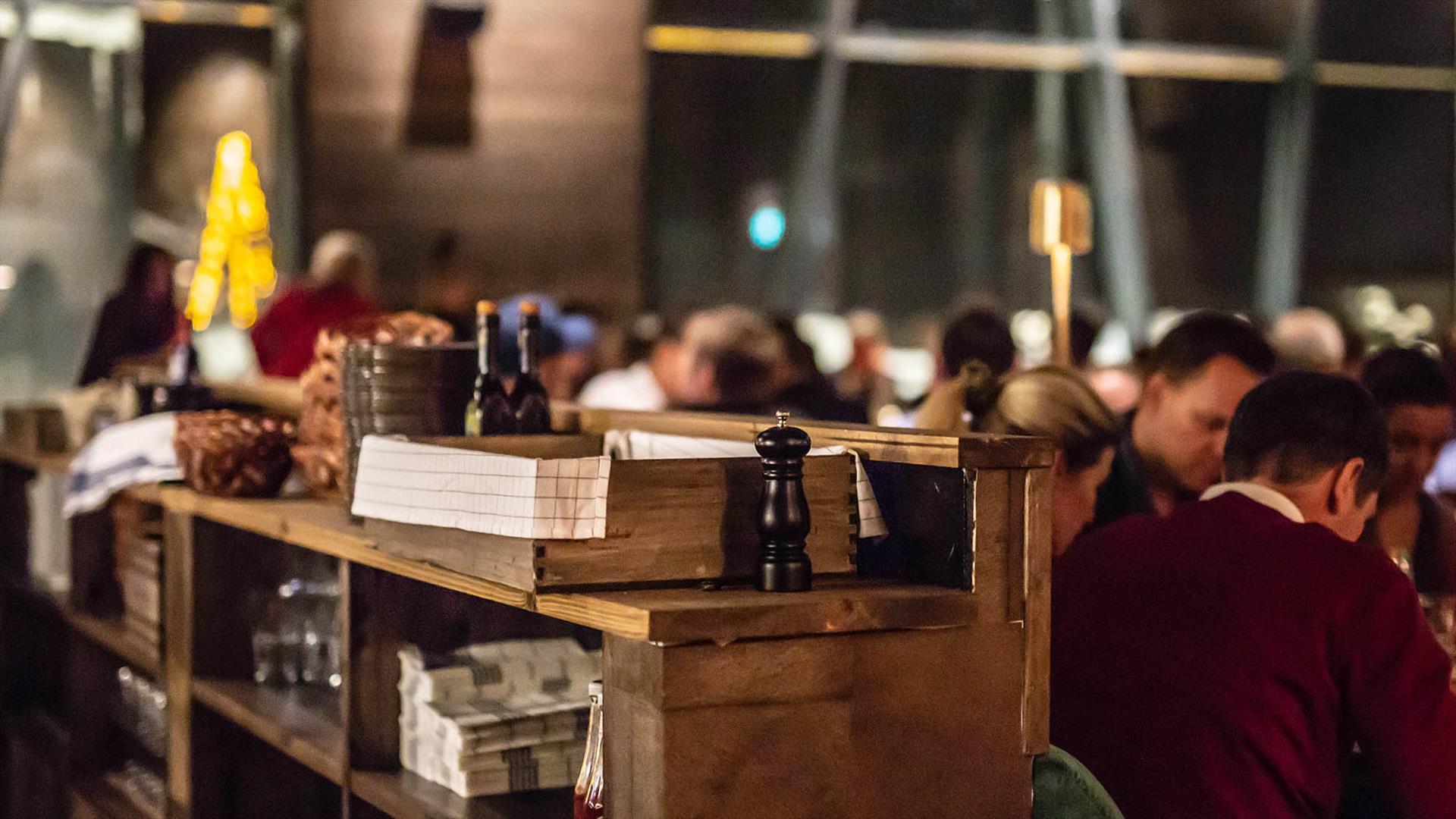 Stilig bilde av en disk i et restaurant med pepperkvern og folk som spiser i bakgrunnen